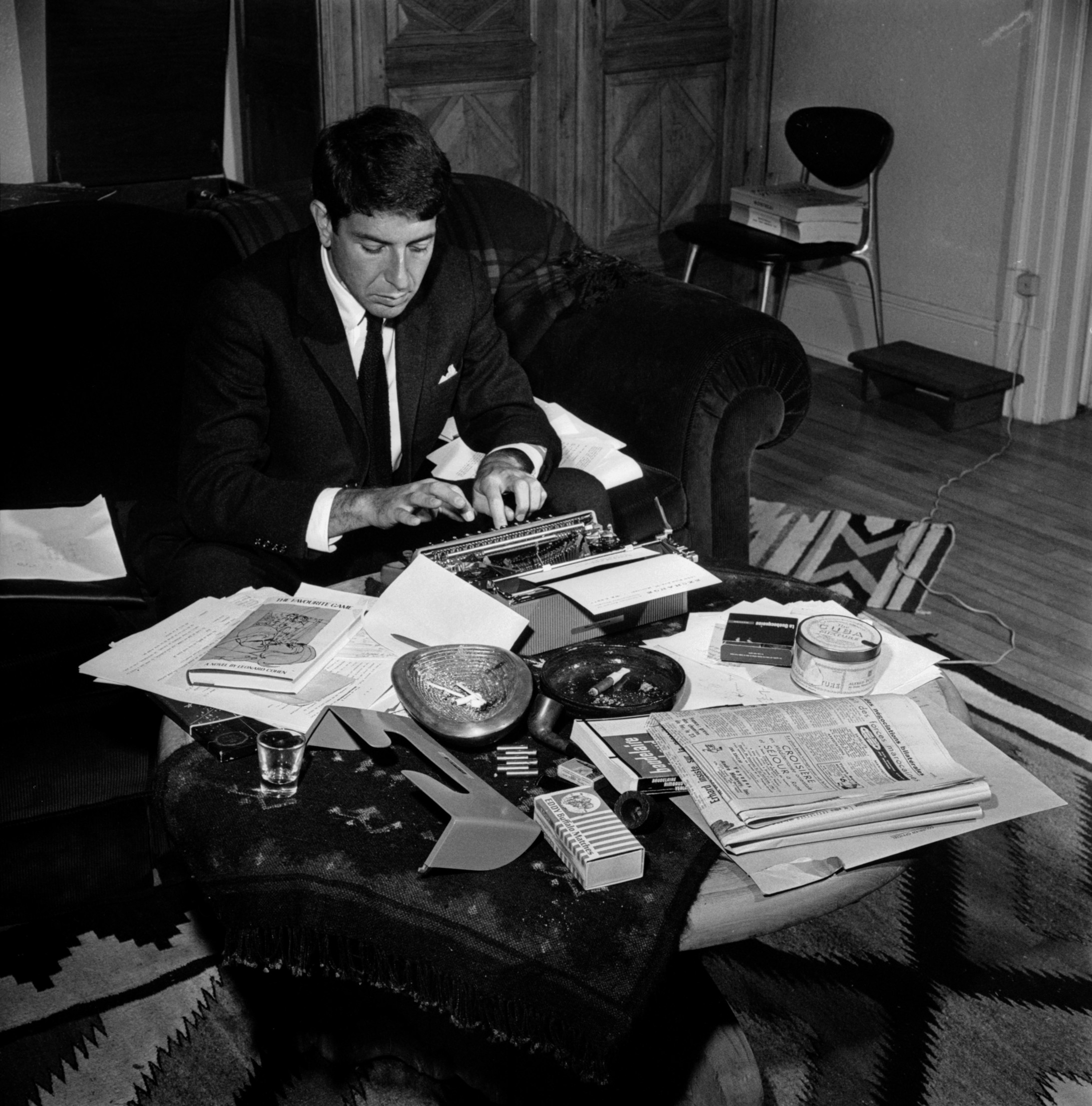 Leonard Cohen 1963 als Poet. Seine Olivetti-Schreibmaschine war ebenso sein Markenzeichen wie später die Gitarre - und natürlich der Anzug. Das Bild stammt aus dem Band: Leonard Cohen, almost young, Eine Bildbiographie mit einem Text von Jens Sparschuh, Schirmer/Mosel 2014. - Dieses Buch ist ein "must have". Foto: Allan R. Leishman