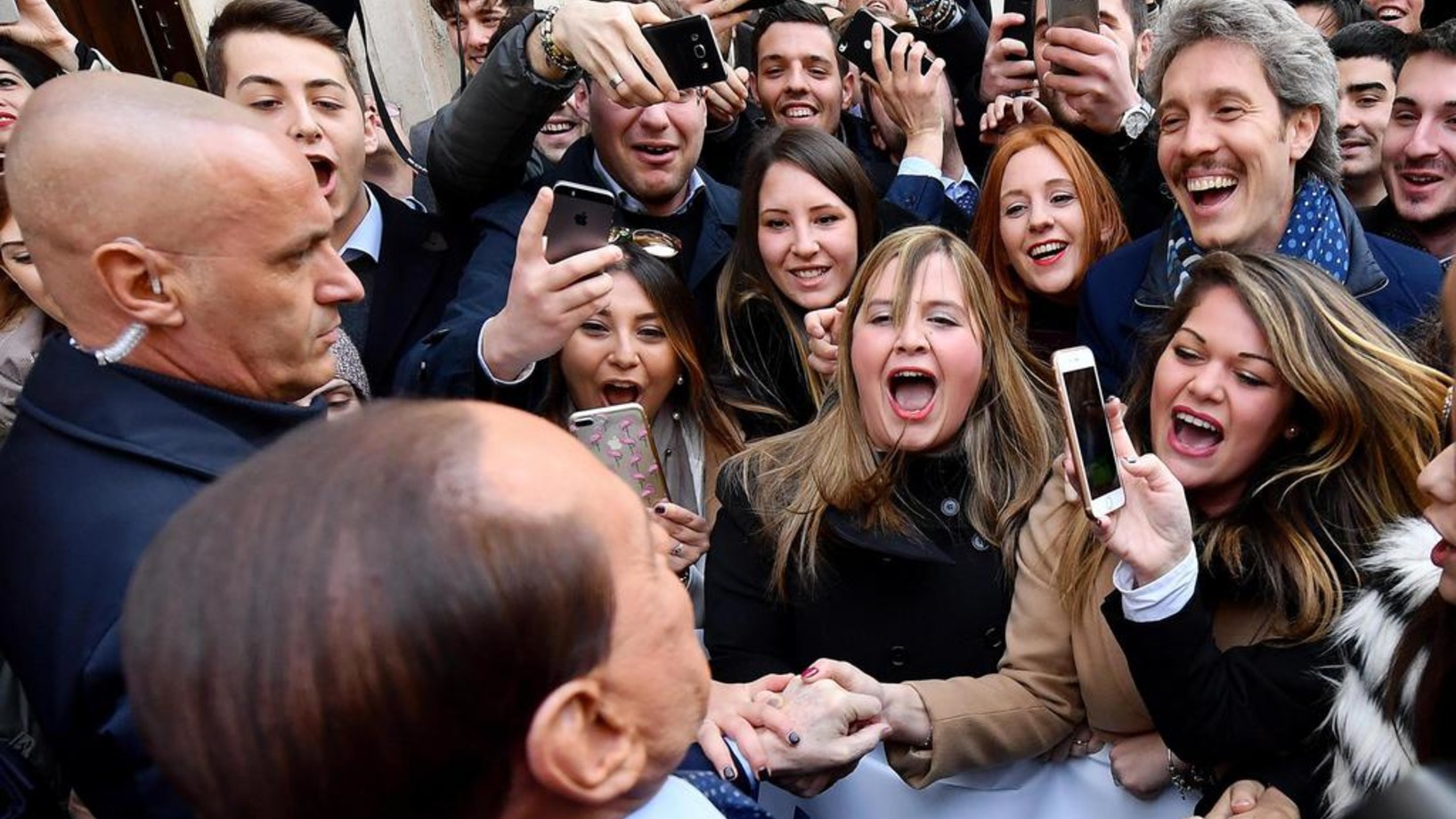 Berlusconi (vorne im Bild) mit jungen Fans in Rom. „Silvio, Silvio“, schreien sie. Berlusconi erklärt ihnen: „Ihr müsst den Wahlzettel nehmen und ein Kreuz bei Forza Italia machen.“ (Foto: Keystone/Ansa/Ettore Ferrari)
