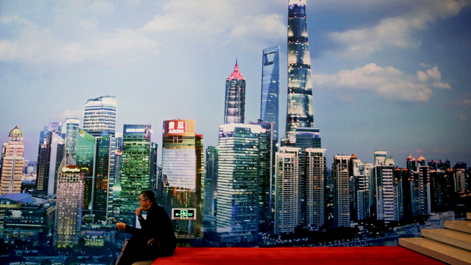Ein Museumsbesucher macht Pause vor dem Bild des Financial District Shanghais, das in der Ausstellung zum 40. Jahrestag der Öffnung und Reform Chinas im Pekinger Nationalmuseum gezeigt wird. (Keystone/AP, Andy Wong)
