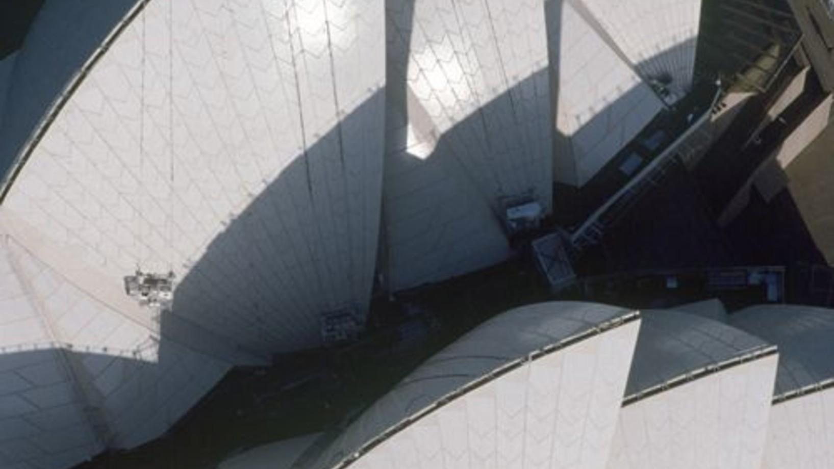 Das Opernhaus der Stadt Sydney
Von neueren Bauwerken beansprucht seit dem Eifelturm wohl keines überzeugender den Rang einer Stadtikone. Stadtikone? Mehr noch, Landesikone: die weissen Segel aus Beton sagen ja heute ebenso lockend „Australien“ wie der rote Inselberg Uluru. Der dänische Architekt Jørn Utzon hatte 1957 den Wettbewerb für das Opernhaus mit einer blossen Skizze gewonnen; deren Verwirklichung ab 1959 stand aber von Anfang an unter keinem guten Stern.

Utzon wurde dazu gedrängt, mit den Bauar…