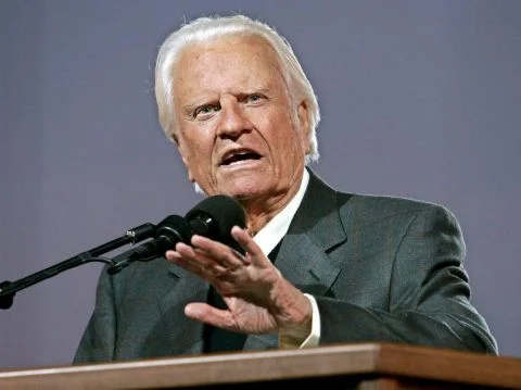 Geburt von Billy Graham, amerikanischer Baptist und Erweckungsprediger, Verbreiter eines fundamentalistisch verstandenen Christentums, das „Maschinengewehr Gottes“, militanter Antikommunist, Kämpfer gegen Homosexualität und Abtreibung, Freund von Martin Luther King, Richard Nixon und George W. Bush. In seinem langen Leben hielt er mehr als 400 Grossveranstaltungen in 185 Ländern (auch in der Schweiz) ab und soll damit mehr als 200 Millionen Menschen erreicht haben. (Foto: Keystone/EPA/Peter Foley)