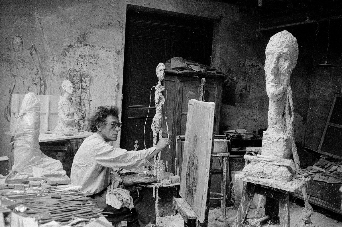 Giacometti beim Malen in seinem Atelier in Paris, daneben La grande tête, Paris, ca. 1957, Foto von Ernst Scheidegger, © 2018 Stiftung Ernst Scheidegger-Archiv, Zürich