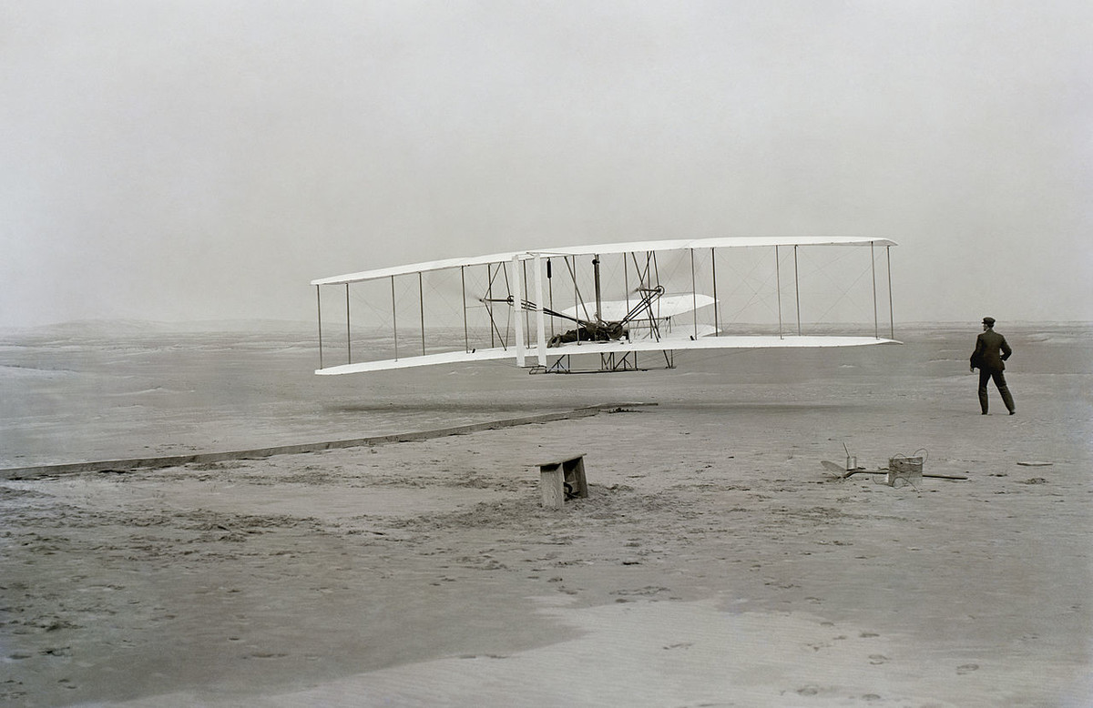 Den amerikanischen Gebrüdern Orville und Wilbur Wright gelingt der erste Flug mit einem von einem Motor getriebenen Flugzeug. Er dauert zwölf Sekunden. Das Flugzeug legt eine Strecke von 37 Metern zurück. Zuvor hatten die Gebrüder jahrelang mit Gleitern experimentiert. Das Bild zeigt den ersten Motorflug in der Geschichte. (Foto: Library of Congress) 