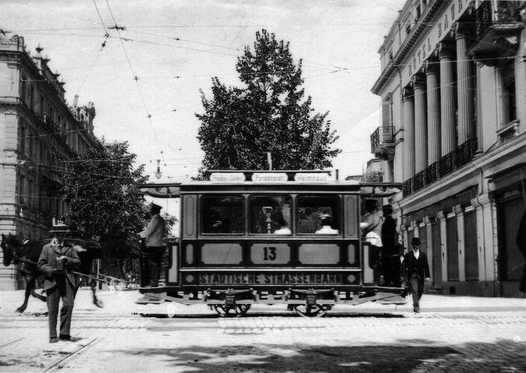 Der gelbe Wagen Nr. 13 fährt von der Poststrasse in den Paradeplatz ein. Die Fahrleitungen für das elektrische Tram sind schon montiert (Bild: Baugeschichtliches Archiv der Stadt Zürich)