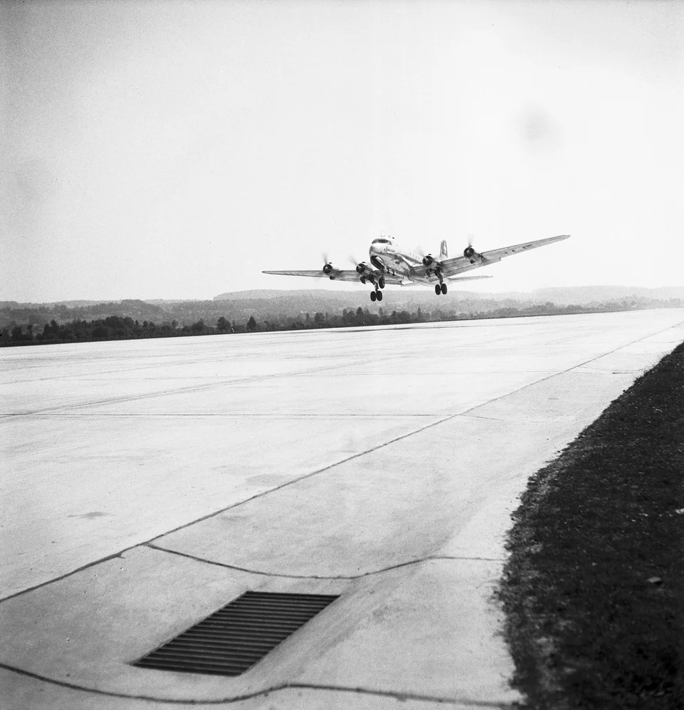 Kloten ist nach Genf der zweite in Betrieb genommene schweizerische Interkontinentalflughafen. Zuvor starteten und landeten die Flugzeuge auf dem Flugplatz Dübendorf. Als erste Piste in Kloten wird die 1900 m lange Westpiste 10/28 in Betrieb genommen werden. Das Bild zeigt die Ankunft der ersten von Dübendorf kommenden Swissair-Maschine in Kloten. Sie startete anschliessend Richtung London. Am 17. November 1948 erfolgt die Inbetriebnahme der 2600 m langen Blindlandepiste 16/34 (Piste mit Instrumentenlandes…