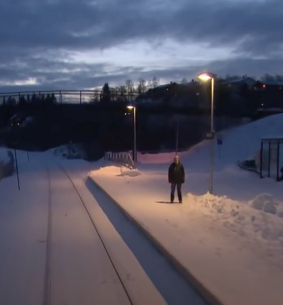 Kurz vor dem Ende der Strecke hält der Zug ein letztes Mal in einem Vorort von Bodø. Ein Mann wartet in der Dunkelheit, um die letzten 2 km zum Endbahnhof mitzufahren – km 727