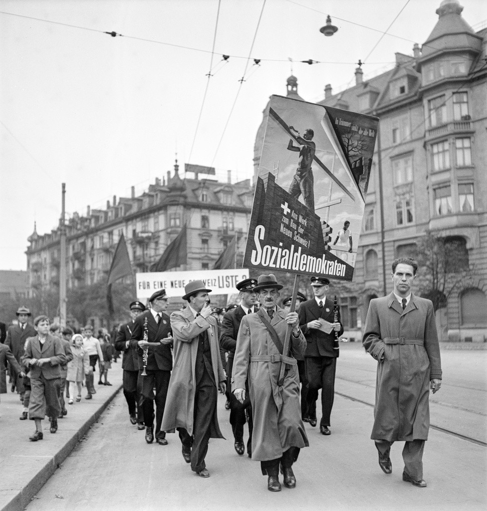 Mitglieder der Sozialdemokraten marschieren vor den National- und Staenderatswahlen im Oktober 1943 mit Bannern durch Zürich. Auf dem Banner steht: «In Trümmer sinkt die alte Welt - Ans Werk zum Bau der neuen Schweiz. Sozialdemokraten». (Foto: Keystone/Photopress-Archiv/MR.)
