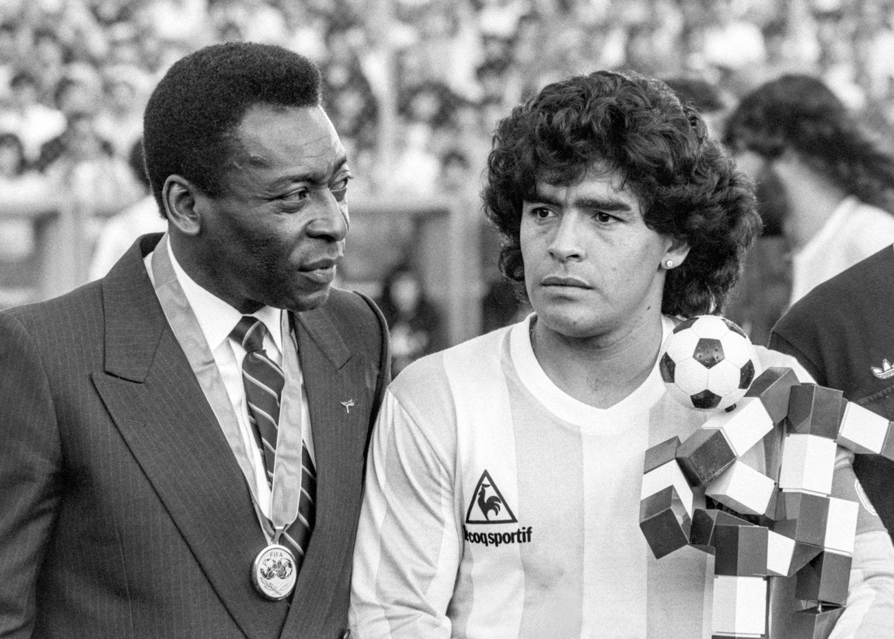 Pele, links, wird am 10. Juni 1987 im Hardturm Stadion in Zuerich anlaesslich des Spiels zwischen Italien und Argentinien von der FIFA wegen seiner Verdienste um den Fussball mit einer Medaille geehrt, und Diego Maradona, rechts, Captain der argentinischen Mannschaft, erhaelt das Maskottchen fuer die WM 1990 in Italien als Geschenk. (KEYSTONE/Str) 