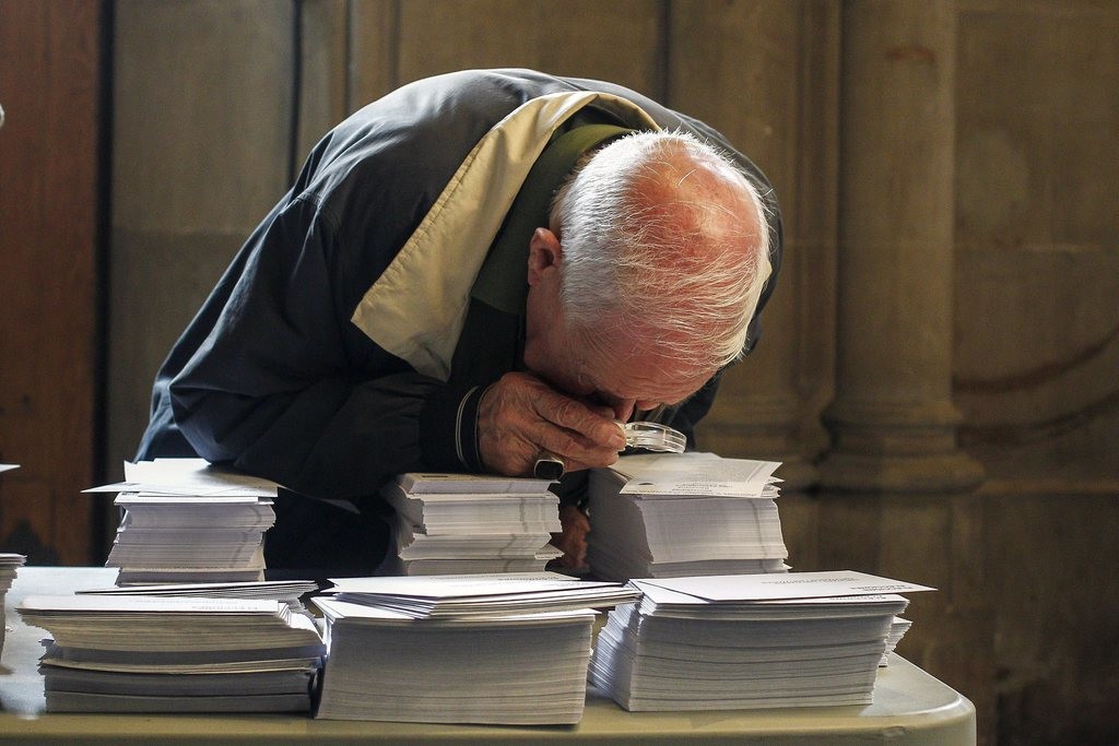 Das Bild vom Sonntagvormittag zeigt einen älteren Mann in einem Abstimmungslokal in Barcelona, der die Wahlzettel sehr genau studiert. (Foto: Keystone/EPA/Quique Garcia)