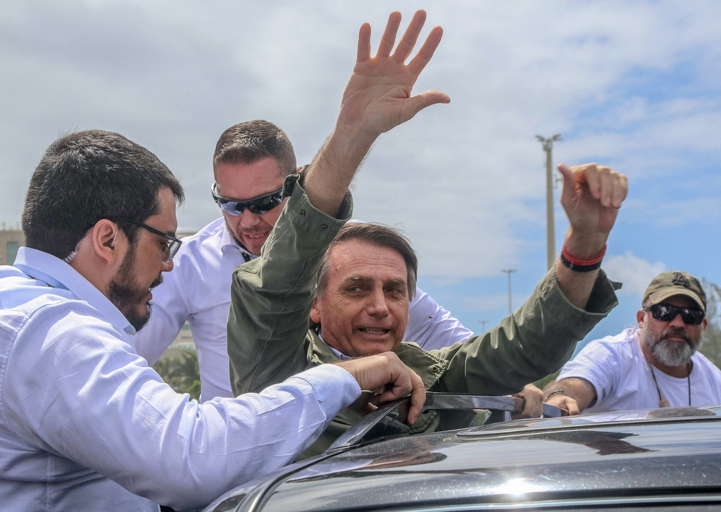 Der ultrarechte Jair Bolsonaro gewinnt mit 55 Prozent der Stimmen die Präsidentschaftswahl. Bolsonaros Gegner bezeichnen ihn als eine Gefahr für die junge Demokratie und fürchten, er werde das Land in Richtung einer Militärdiktatur treiben. Bolsonaro am Wahltag mit Leibwächtern vor einem Wahllokal in Rio (Foto: Keystone/EPA/Fernando Maia)