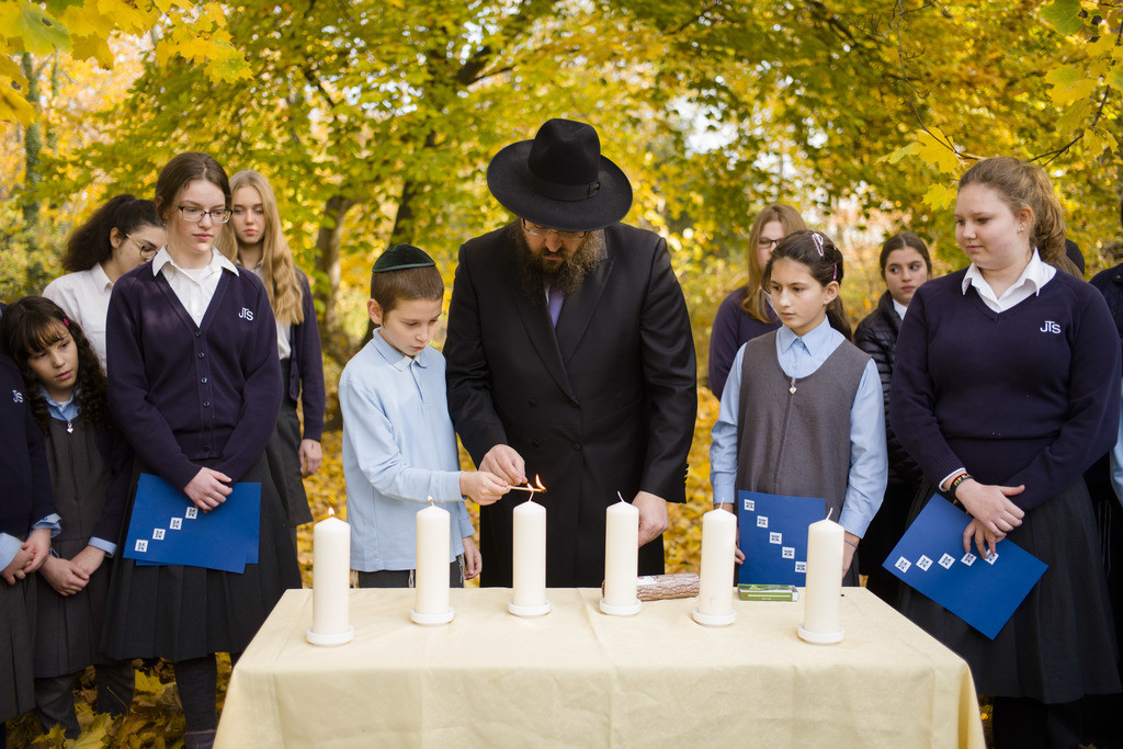 Rabbi Yehuda Teichtal, center, light candles with students during an event to commemorate the victims of the Nov. 9, 1938 terror against the Jews in Germany at the Jewish Traditional School in Berlin, Wednesday, Nov. 7, 2018. On the event the school also remember to the victims of the anti-Semitic attack at the Tree of Life Synagogue in Pittsburgh, United States, on Saturday, Oct. 27, 2018. (AP Photo/Markus Schreiber)