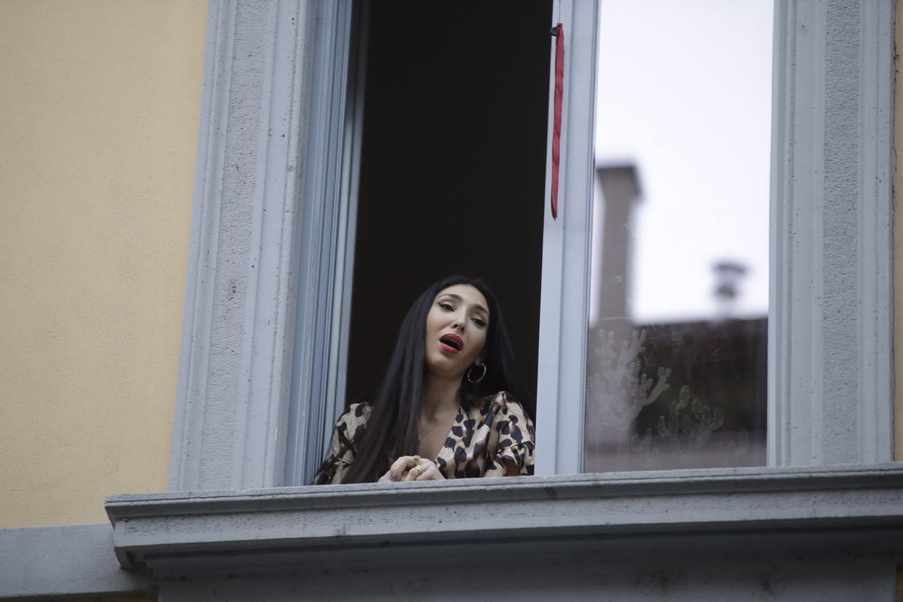 Opera singer Laura Baldassari leans out of her window to sing during a flash mob launched throughout Italy to bring people together and try to cope with the emergency of coronavirus, in Milan, Italy, Friday, March 13, 2020. Italians have been experiencing yet further virus-containment restrictions after Premier Giuseppe Conte ordered restaurants, cafes and retail shops closed after imposing a nationwide lockdown on personal movement. For most people, the new coronavirus causes only mild or moderate symptom…