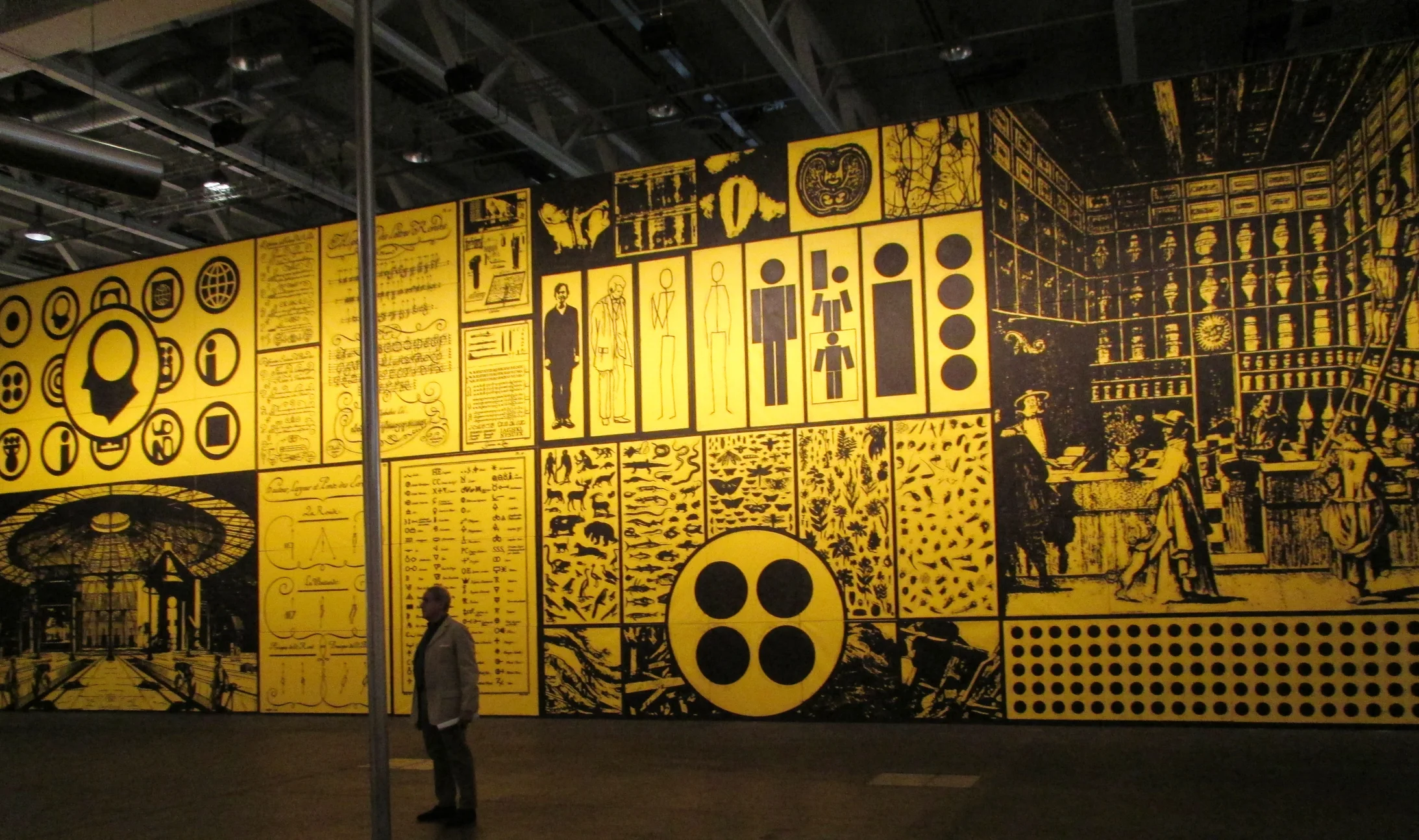 Blick auf das gigantische Gemälde (22 X 7 m) des Amerikaners Matt Mullican. Die in Gelb und Schwarz gehaltene Arbeit (Two into One becomes Three) besteht aus 70 einzelnen Leinwänden. die sich zu einem monumentalen Panorama zusammenfügen.    
(Bild: André Pfenninger)