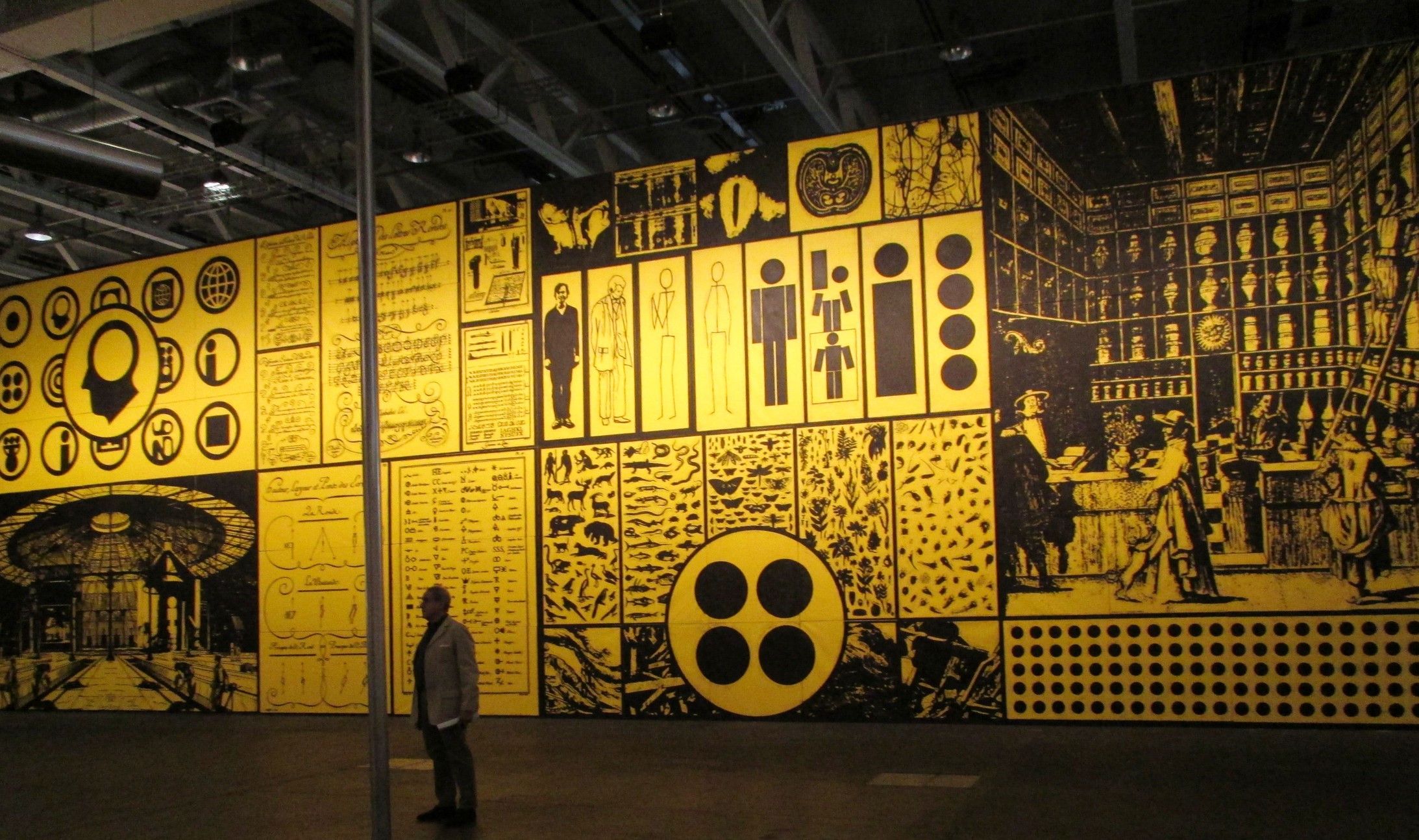 Blick auf das gigantische Gemälde (22 X 7 m) des Amerikaners Matt Mullican. Die in Gelb und Schwarz gehaltene Arbeit (Two into One becomes Three) besteht aus 70 einzelnen Leinwänden. die sich zu einem monumentalen Panorama zusammenfügen.    
(Bild: André Pfenninger)