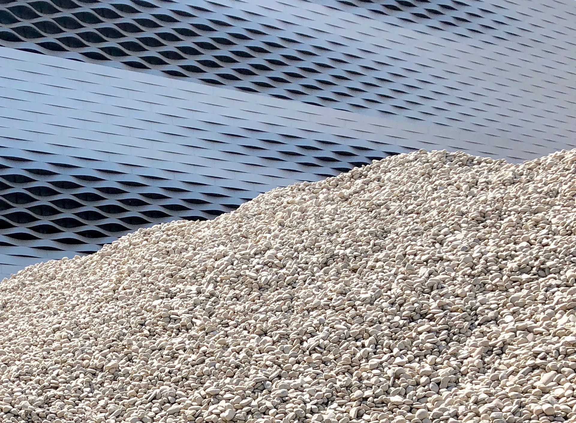 Basel Messeplatz: der Kieshaufen von Lara Almarcegui vor der Fassade des Messegebäudes von Herzog & de Meuron