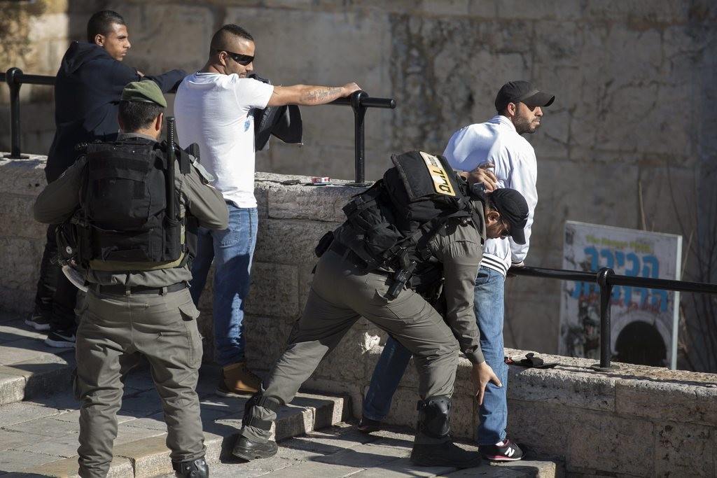 Israelische Sicherheitskräfte durchsuchen junge Palästinenser beim Damaskus-Tor in Ostjerusalem. Israel hat seine Sicherheitsmassnahmen verstärkt, nachdem am Mittwoch drei israelische Polizistinnen von Palästinensern mit Messern angegriffen worden waren. Eine Polizistin erlag ihren Verletzungen. (Foto: Keystone/EPA/Jim Hollander)
