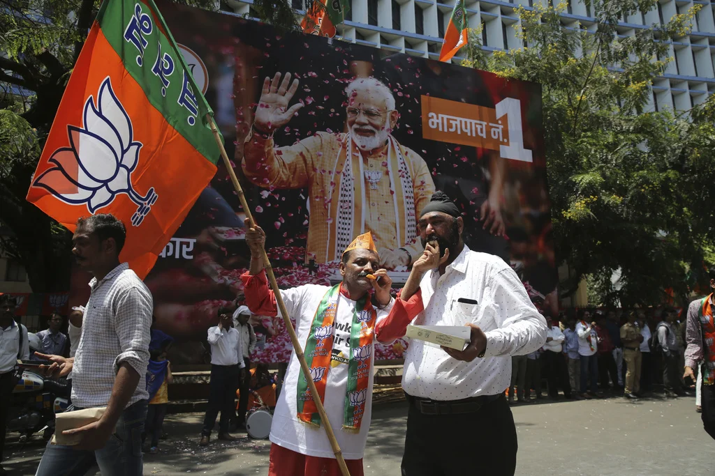 Anhänger von Modis BJP feiern am Donnerstag in Mumbai den Triumpf ihrer Partei. Im Hintergrund ein überlebensgrosses Plakat des Premierministers. (Foto: Keystone/AP/Rafiq Maqbool) 