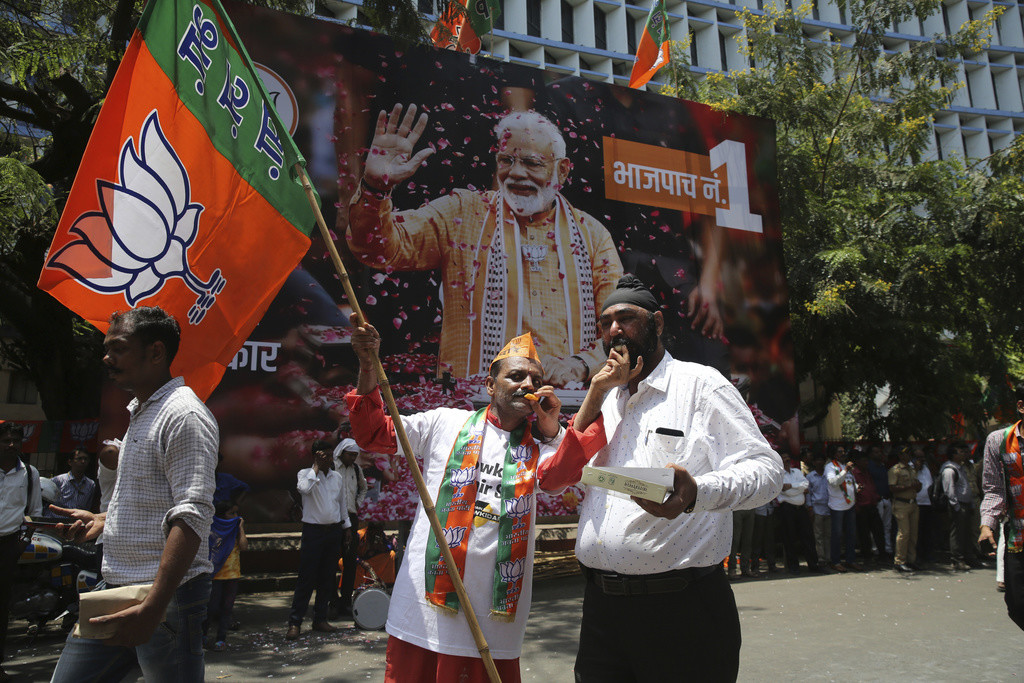 Anhänger von Modis BJP feiern am Donnerstag in Mumbai den Triumpf ihrer Partei. Im Hintergrund ein überlebensgrosses Plakat des Premierministers. (Foto: Keystone/AP/Rafiq Maqbool) 