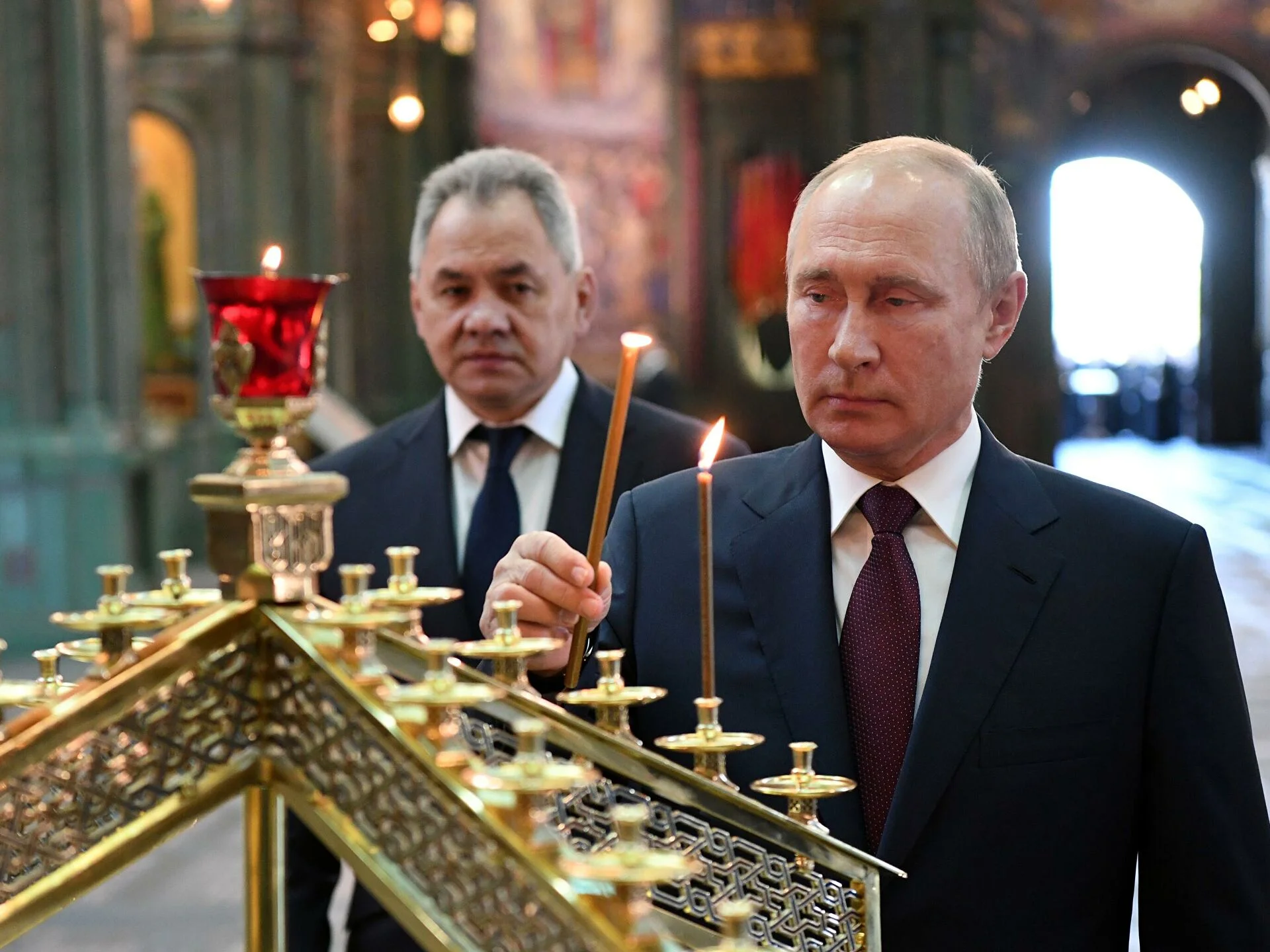 Putin entzündet bei der Einweihung des Tempels der Streitkräfte eine Kerze. Dahinter sein Verteidigungsminister Schoigu.