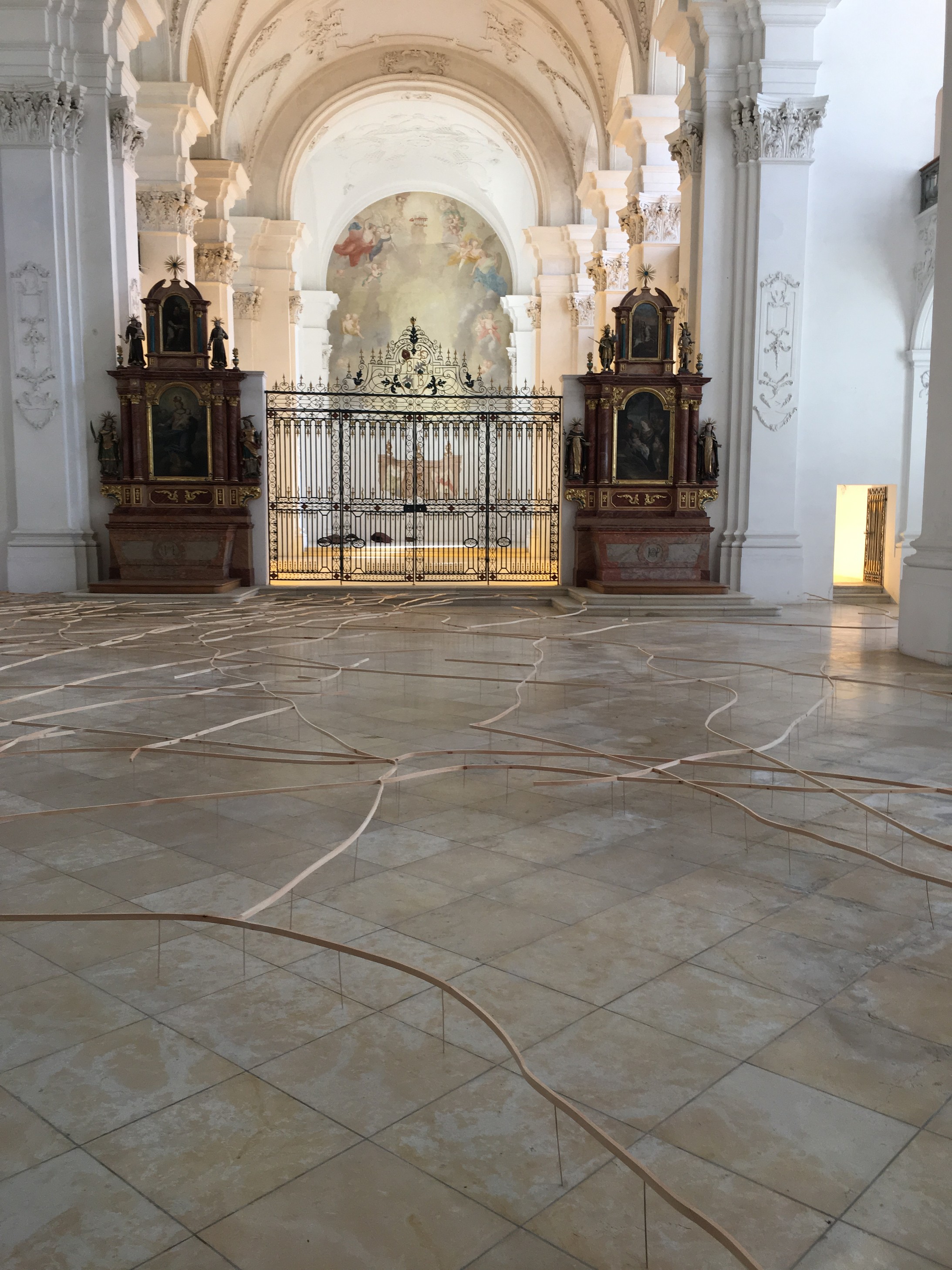 Das Liniengeflecht aus hellem Arvenholz knapp über dem Boden des Kirchenschiffs der Abteikirche Bellelay