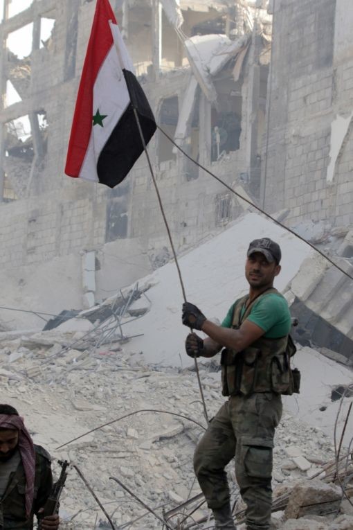Ein Anhänger von Präsident Asad hisst die syrische Flagge. Nach sechs Jahren Bürgerkrieg kontrolliert die Armee von Präsident Asad wieder die syrische Hauptstadt und ihre Vororte. Zuvor waren die letzten Verbände des Islamischen Staats aus dem Süden der Stadt abgezogen. Weite Teile der Stadt liegen in Trümmern. (Foto: Keystone/AP)