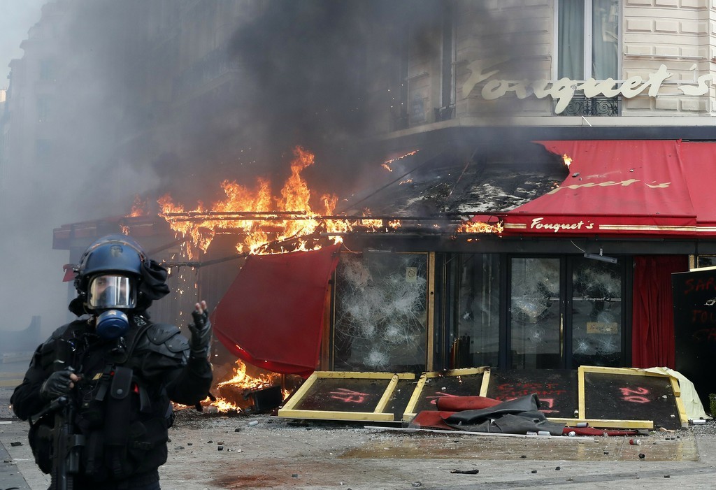 Das Nobelrestaurant Le Fouquet's (Foto: Keystone/AP/Christophe Ena)Tausende Gelbwesten haben am Samstag die Champs-Élysées verwüstet. 
Zahlreiche Autos brannten, Nobelboutiquen, wie ein Geschäft der Luxusmarke Longchmap, wurden eingeschlagen und geplündert. Das Prominentenrestaurant Le Fouquet’s wurde teils in Brand gesteckt. Die Polizei setzte Tränengas und Wasserwerfer ein. Mehrere Zeitungskioske brannten aus.
