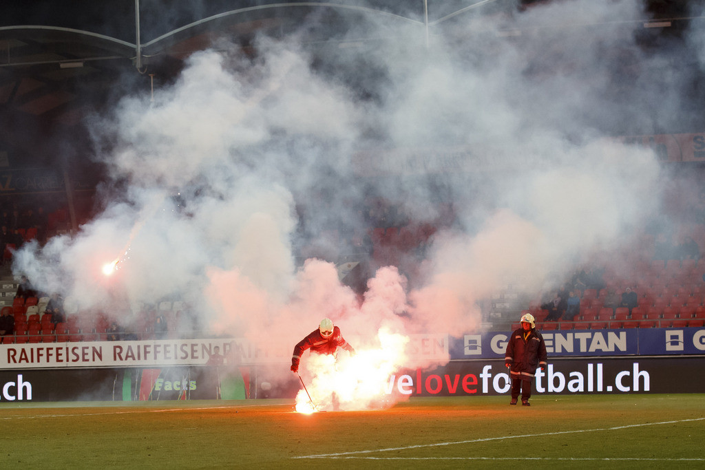 Firefighters remove light flares launching by Grasshopper's supporters, during the Super League soccer match of Swiss Championship between FC Sion and Grasshoppers Club, at the Stade de Tourbillon stadium, in Sion, Switzerland, Saturday, March 16, 2019. (KEYSTONE/Salvatore Di Nolfi)