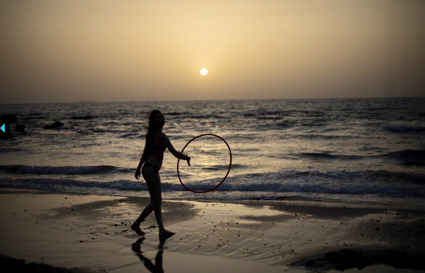 Eine Frau am Strand von Tel Aviv mit einem Hula-Hoop-Ring. Während mehreren Tagen werden über 40 Grad gemessen. (Foto: Keystone/AP/Ariel Schalit)
