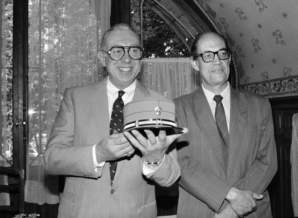 Das ZDF strahlt die erste «Derrick»-Folge mit Horst Tappert in der Titelrolle aus. Sie trägt den Titel „Waldweg“. „Derrick“ ist die meistverkaufte Serie in der deutschen Fernsehgeschichte. Insgesamt wurden 281 Folgen produziert. Horst Tappert starb 2008. Das Bild zeigt ihn am 1. September 1989 in Lausanne mit dem damaligen Westschweizer Fersehdirektor Guillaume Chenevière und einer Waadtländer Dienstmütze. Tappert war passionierter Dienstmützensammler. (Foto: Keystone/Str)