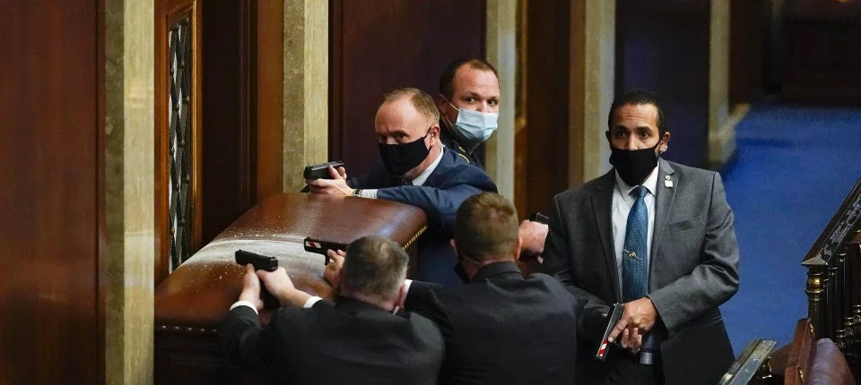 U.S. Capitol Police with guns drawn stand near a barricaded door as protesters try to break into the House Chamber at the U.S. Capitol on Wednesday, Jan. 6, 2021, in Washington. (AP Photo/Andrew Harnik) 