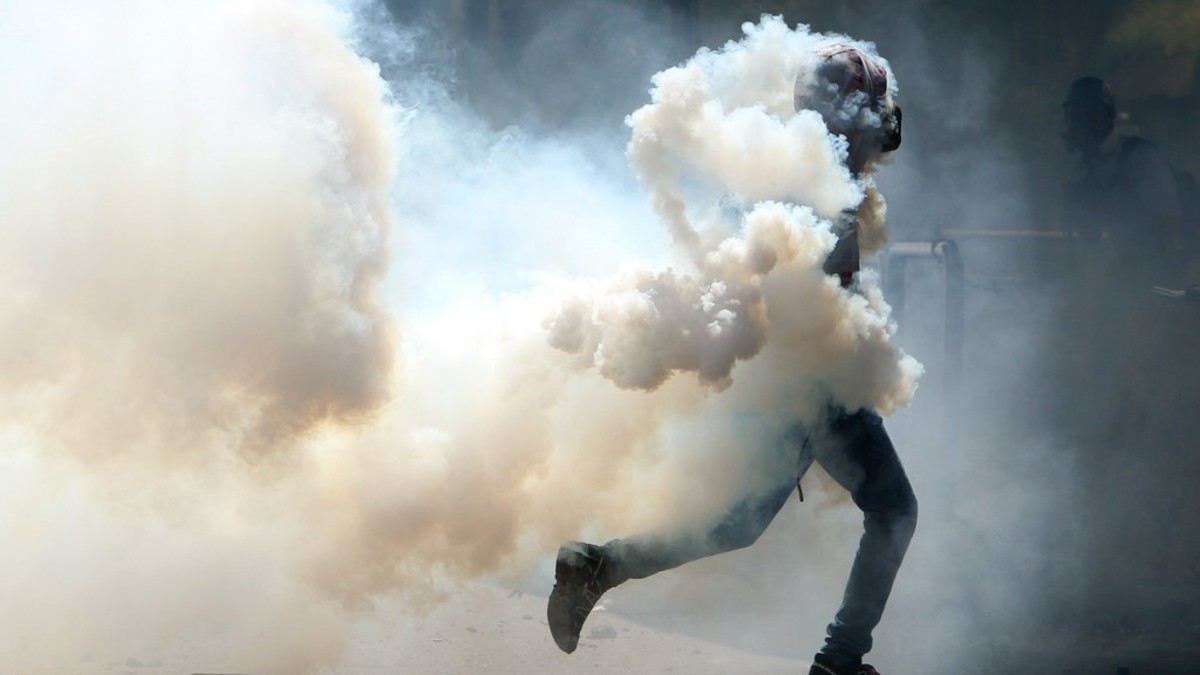 Ein Demonstrant, eingehüllt in Tränengas, am Freitag in Caracas. (Foto: Keystone/EPA/Mauricio Duenas Castenada)