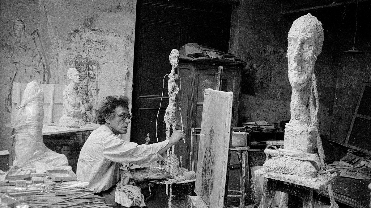 Giacometti beim Malen in seinem Atelier in Paris, daneben La grande tête, Paris, ca. 1957, Foto von Ernst Scheidegger, © 2018 Stiftung Ernst Scheidegger-Archiv, Zürich