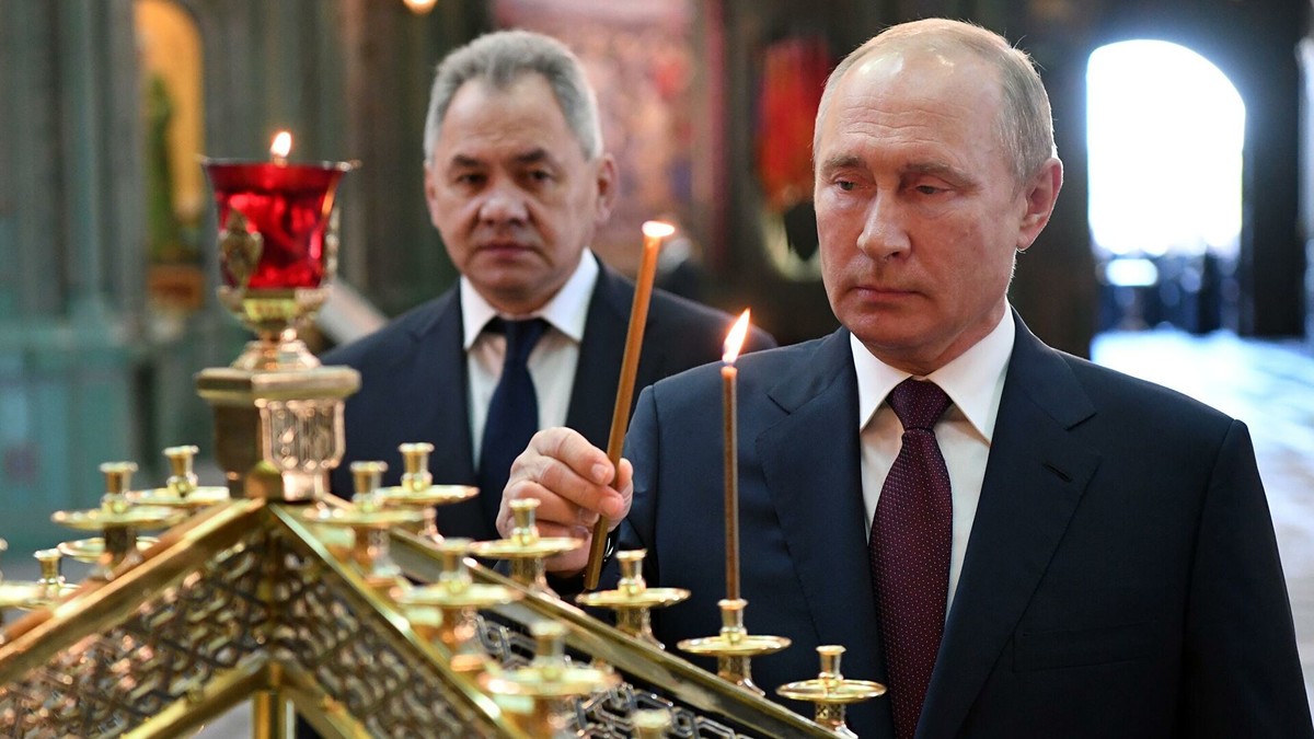 Putin entzündet bei der Einweihung des Tempels der Streitkräfte eine Kerze. Dahinter sein Verteidigungsminister Schoigu.