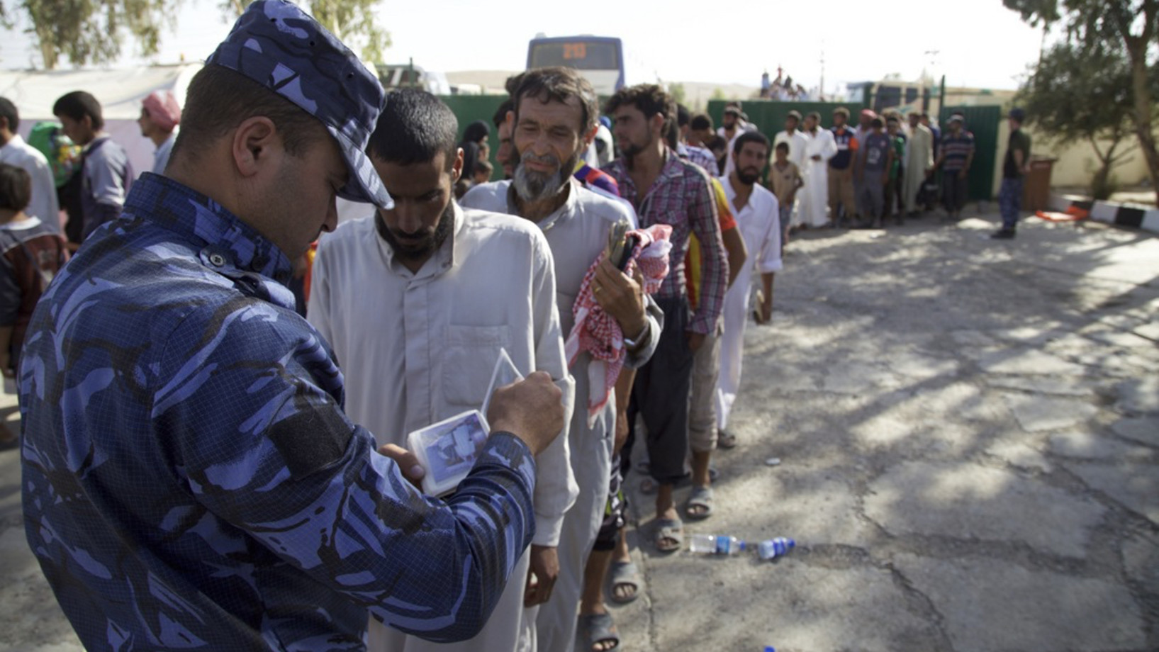 Ein irakischer Polizist kontrolliert eine Gruppe von Zivilpersonen, die sich an einem Sammelpunkt für Geflohene in einem Vorort von Tal Afar eingefunden haben. Die letzte vom IS beherrschte Stadt des Irak soll zu 90 Prozent zurückerobert sein. (Foto: Keystone/AP, Valint Szlanko)
