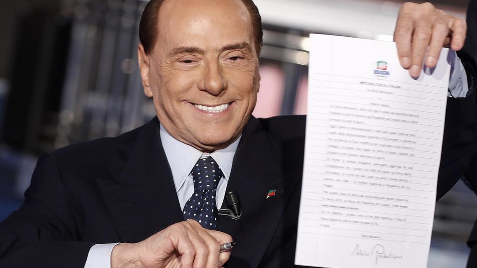 Am Fernsehen zeigt Berlusconi einen von ihm unterschriebenen „Pakt mit Volk“, in dem er verspricht, die italienische Arbeitslosenquote unter den eursopäischen Durchschnitt zu senken. (Foto: Keystone/Ansa/AP/Riccardo Antimiani)