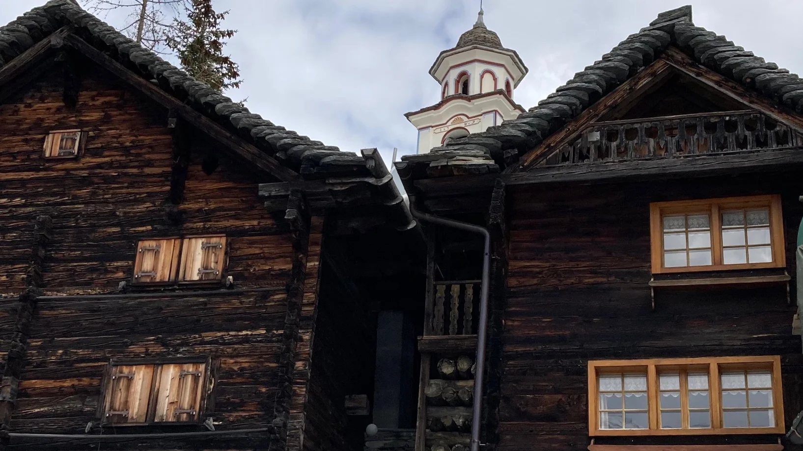 Kirche von Bosco/Gurin hinter typischen Walserhäusern